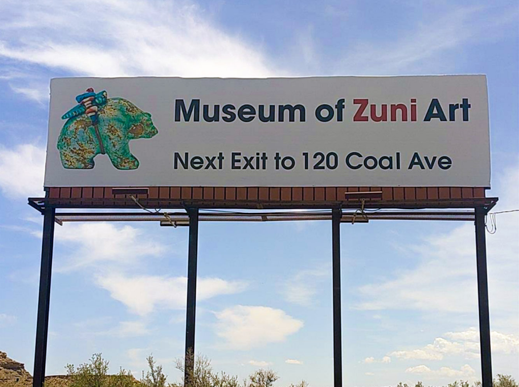 Billboard advertisng "Museum of Zuni Art" with directions and a green colorful graphic