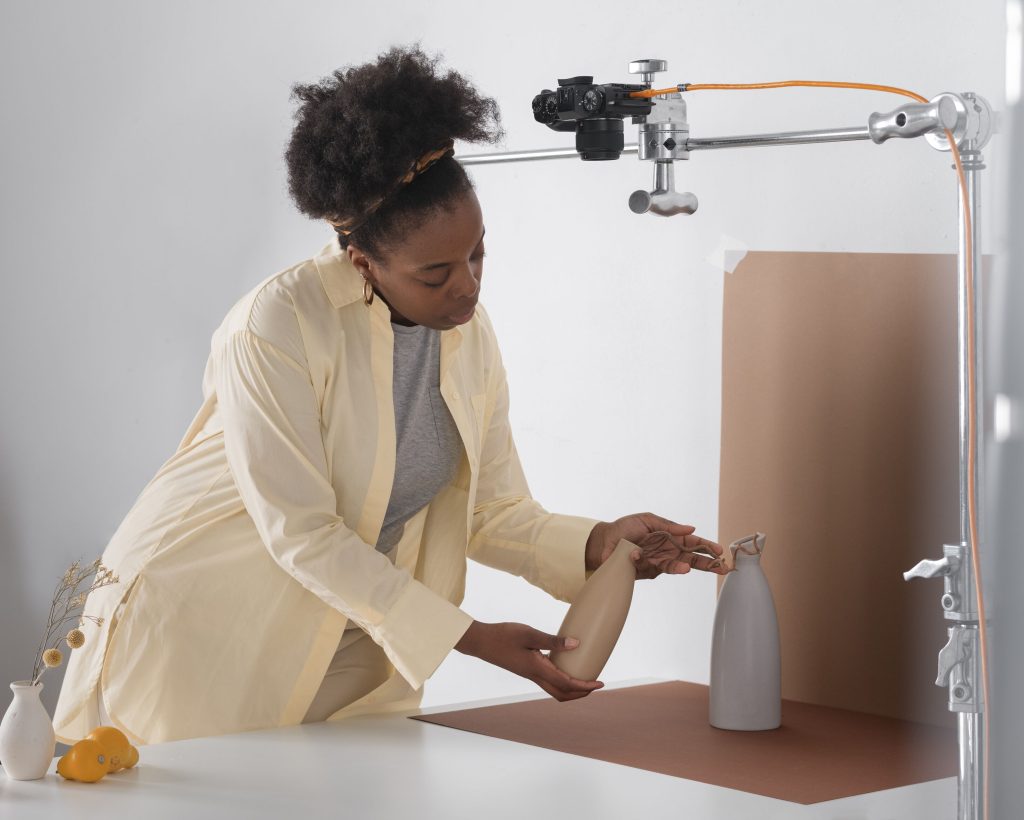 A woman placing a product in front of a screen to be photographed for a marketing campaign