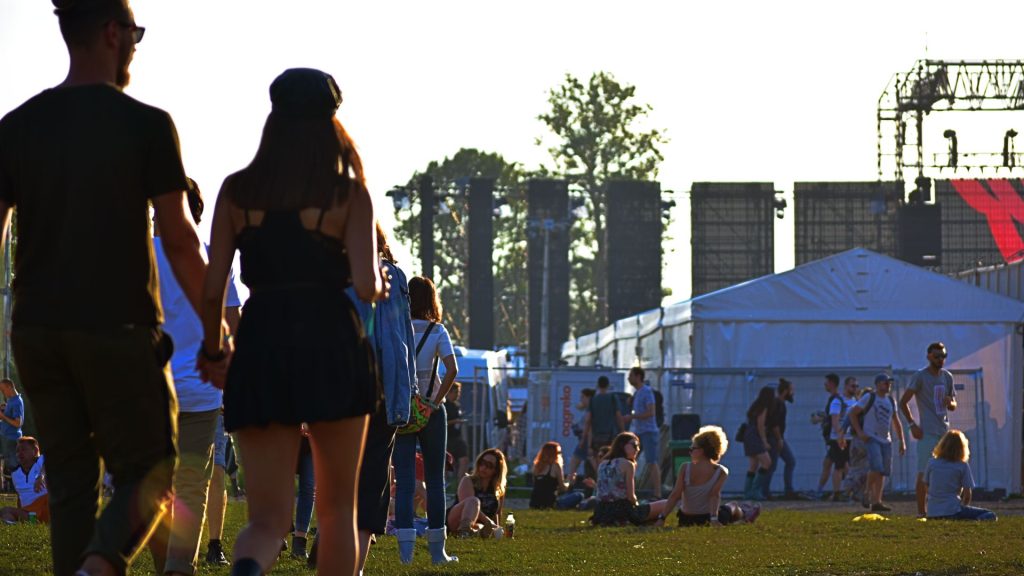 A picture of an event with people walking towards the stage tent