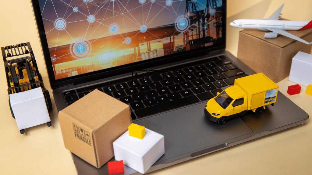 A picture of a laptop with a logistic site on the screen with sites locations identified with a minature truck and boxes on it.