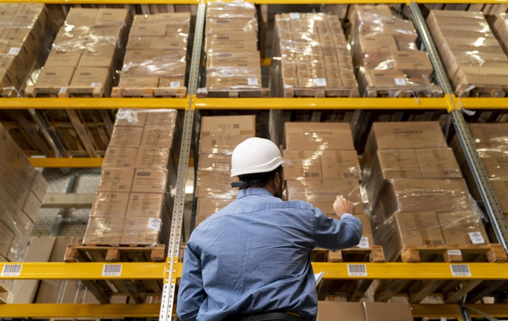 A man looking up at product in a logistics warehouse.