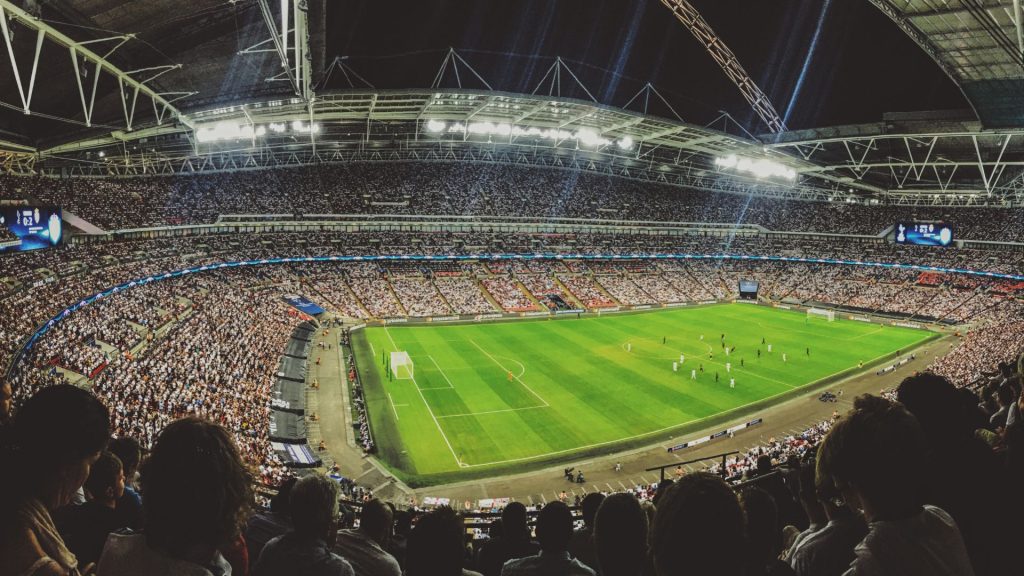 A photo os a sports stadium filled with fans watching a soccer match.