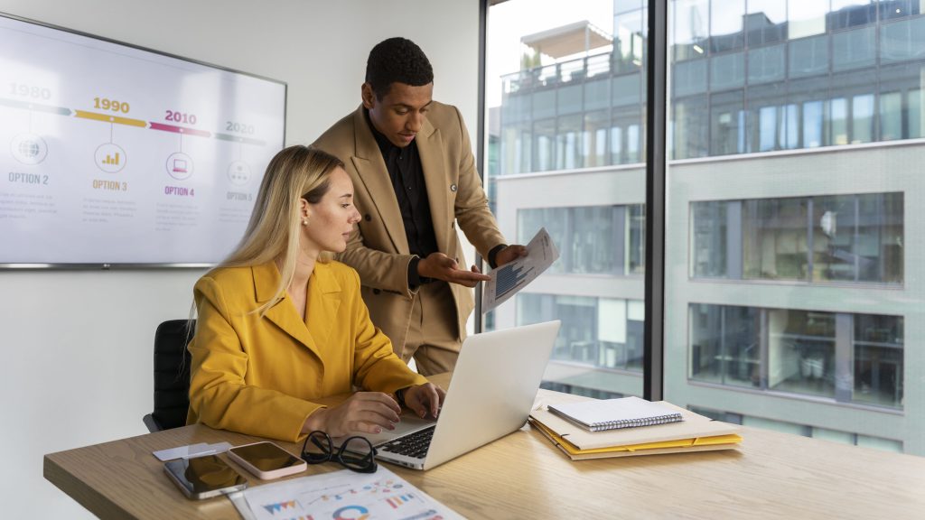 A photo of two professionals looking at metrics to determine if they have the budget to hire a marketing professional.