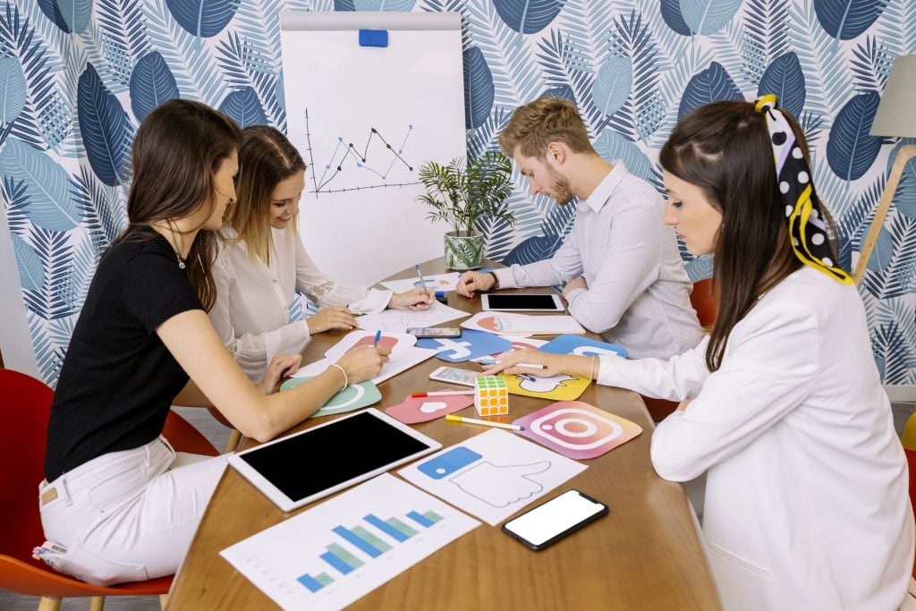 A photo of a marketing team at a desk with a bunch of social media icons and KPIs on it.