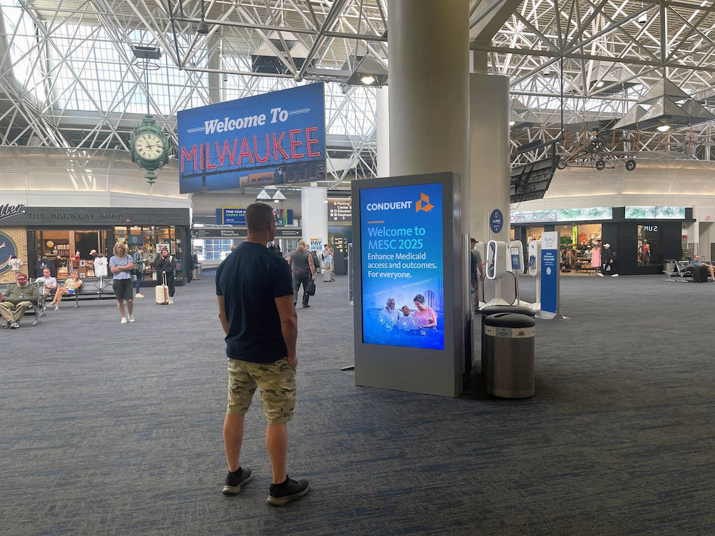 A man looking at a digital airport ad.
