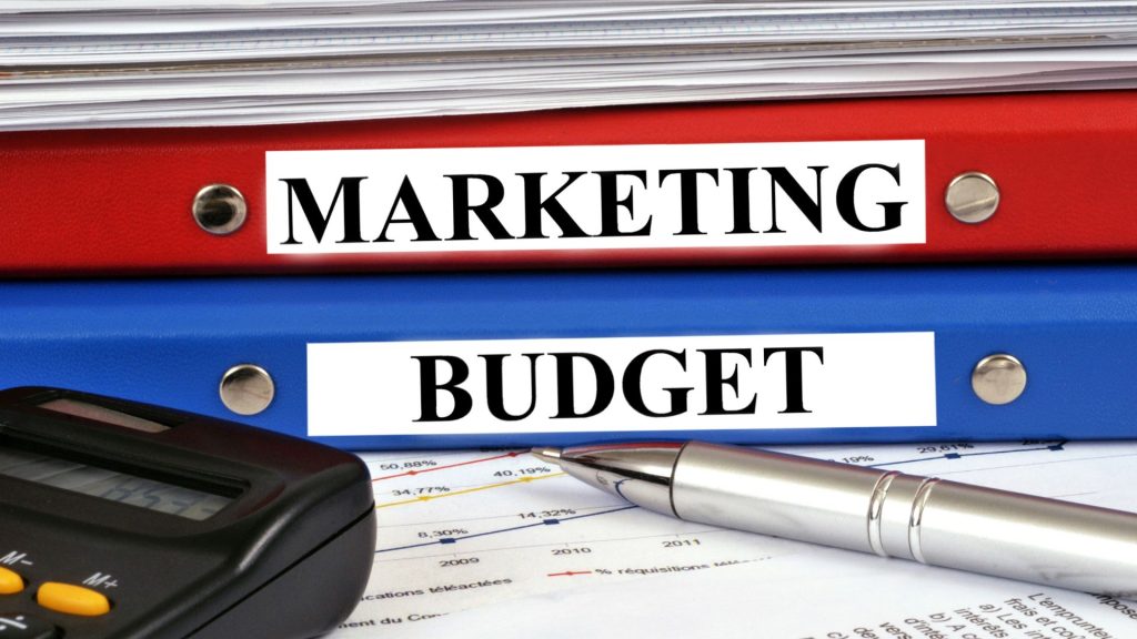 Marketing budget binders and financial documents on a desk, representing planning and allocation strategies such as the 70/20/10 marketing budget rule for organizing marketing spend.