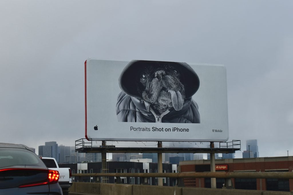 Large roadside billboard displaying a creative brand advertisement above a city highway, illustrating one of the most common types of outdoor advertising used to reach drivers and urban commuters.