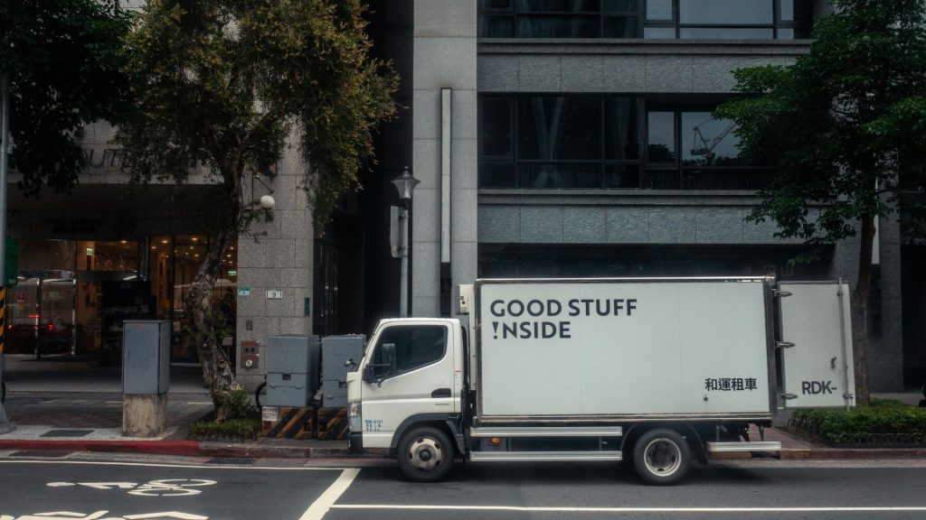 Real-world example of truck advertising on a white delivery van parked in an urban street, featuring the bold "GOOD STUFF INSIDE" slogan for effective local brand messaging.
