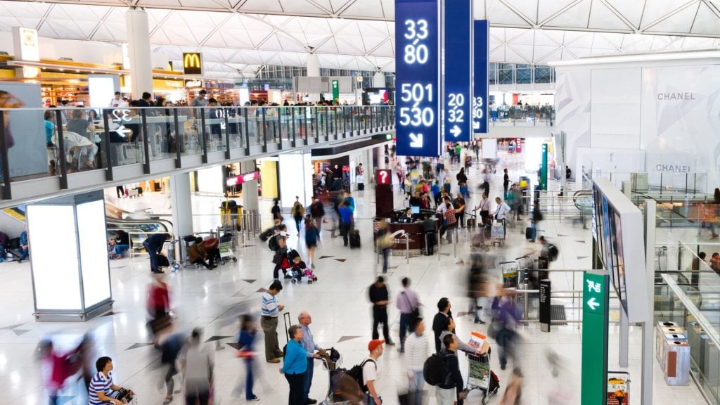 A picture depicting the best airport advertising options with a time-lapse of people at an airport featuring static billboards and digital billboards 