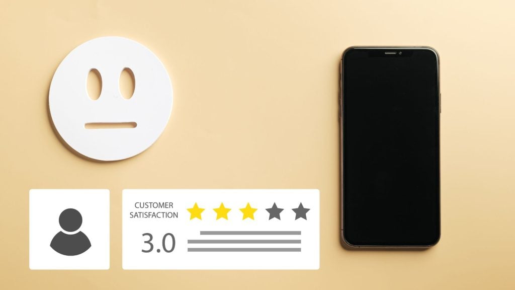 A smartphone rests on a beige desk next to a physical three-star rating graphic and a neutral-face emoji cutout, illustrating the visual feedback components of how to conduct market research.