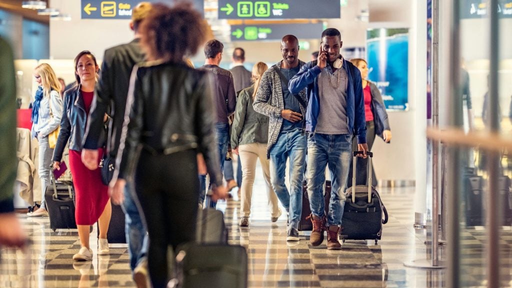 Busy airport terminal filled with people and luggage, illustrating the high-density foot traffic locations used to explain how to evaluate reach and frequency for outdoor media buys.