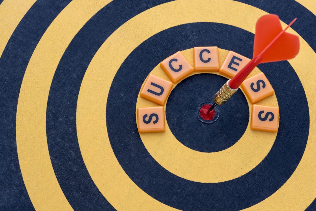 Red dart hitting the center of a target beside the word success, symbolizing goal achievement and precision in a what is GTM strategy plan.