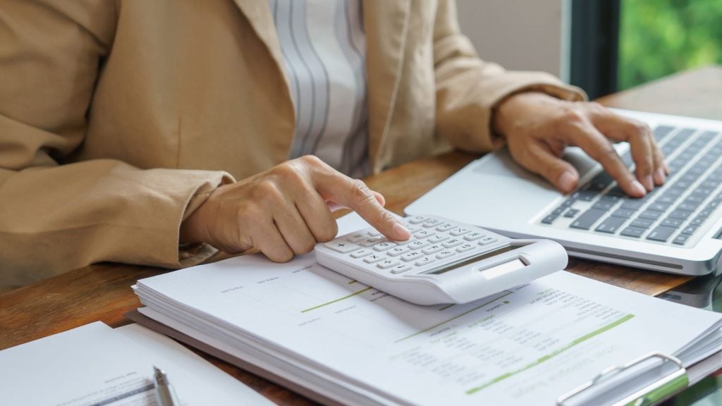 What is ROAS calculation using a calculator, laptop, and financial documents to measure advertising performance and campaign profitability.