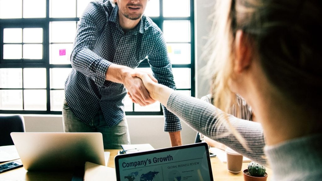 Business professionals shaking hands during a meeting, representing successful B2B advertising strategies that build partnerships and generate qualified leads.